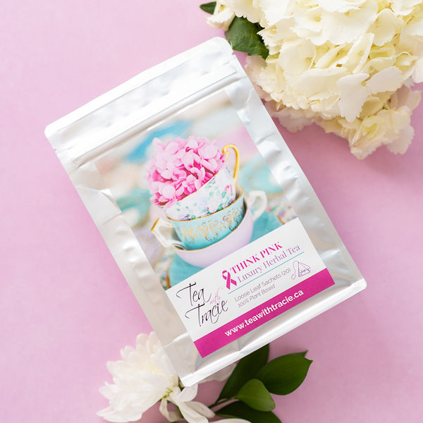Think Pink orange pineapple herbal tea pouch by Tea with Tracie on a pink background with white flowers